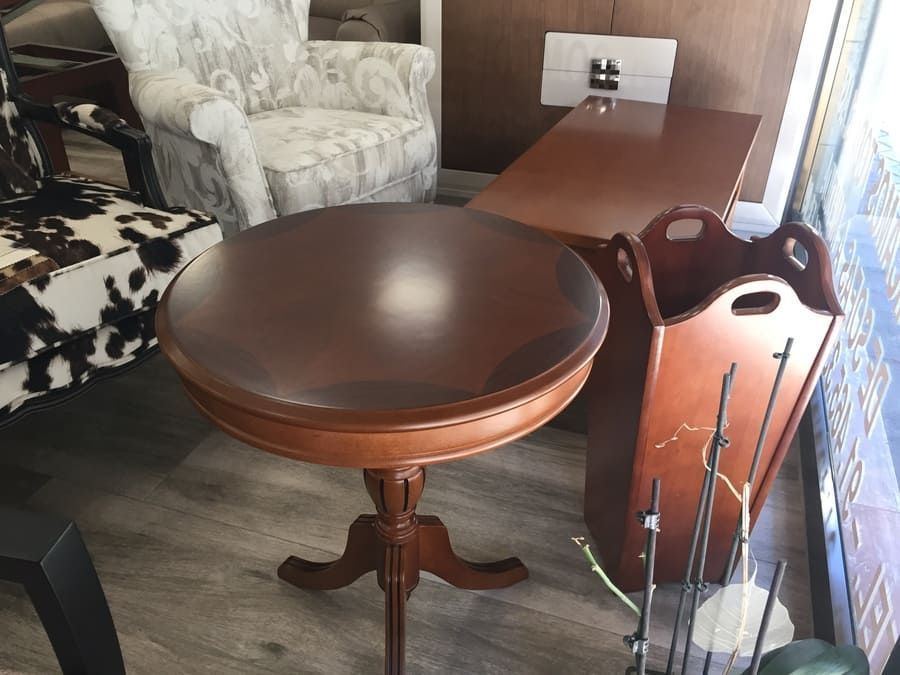 Una mesa redonda de madera con una silla al fondo.