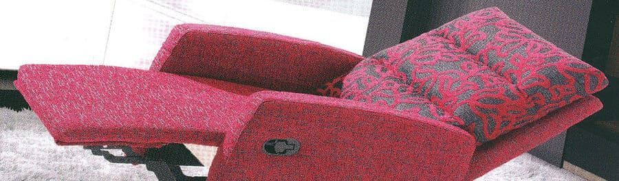 Un sillón reclinable rojo está sobre una alfombra en una sala de estar.