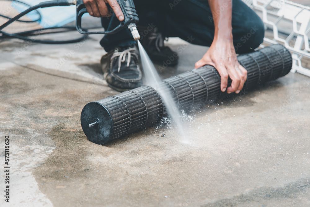 Un homme nettoie un ventilateur avec un nettoyeur haute pression.