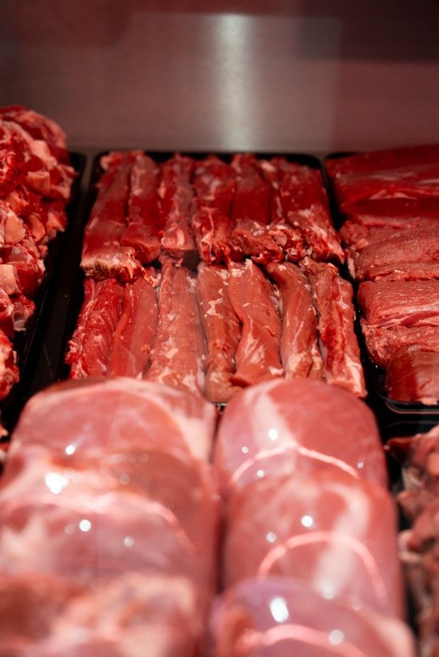 Assortiment de morceaux de viande crue présentés dans une vitrine réfrigérée de boucherie