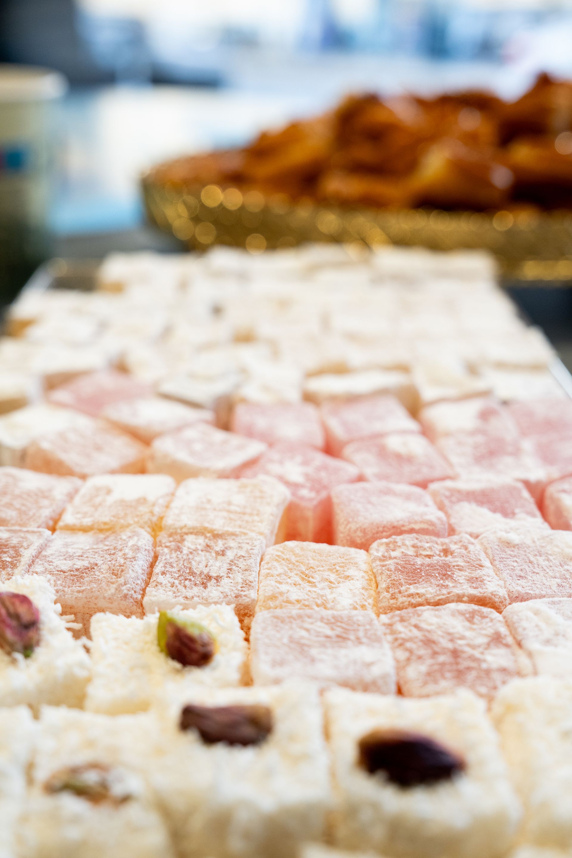 Assortiment de pâtisseries et de bonbons saupoudrés de sucre glace, disposés sur une table de desserts de marché.