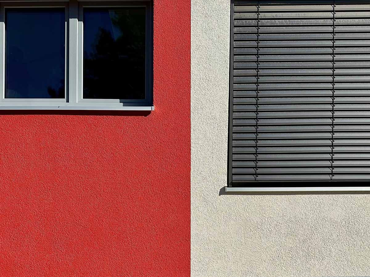 eine rote und weiße Wand mit einem Fenster und einer schwarzen Jalousien - Referenzen von BAUSON GmbH aus Gräfenhainichen