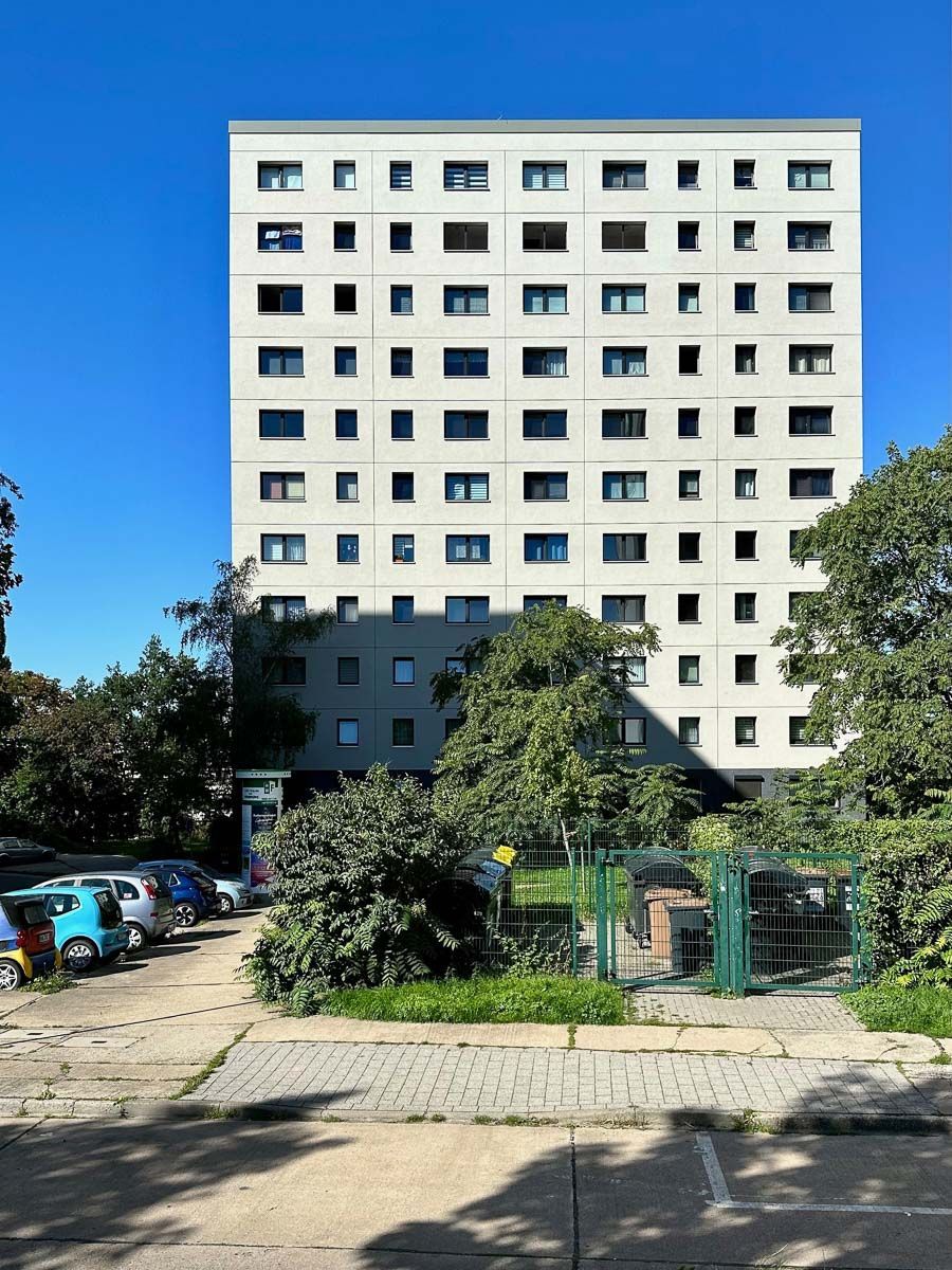 ein großes weißes Gebäude mit vielen Fenstern steht neben einem Parkplatz - Referenzen von BAUSON GmbH aus Gräfenhainichen