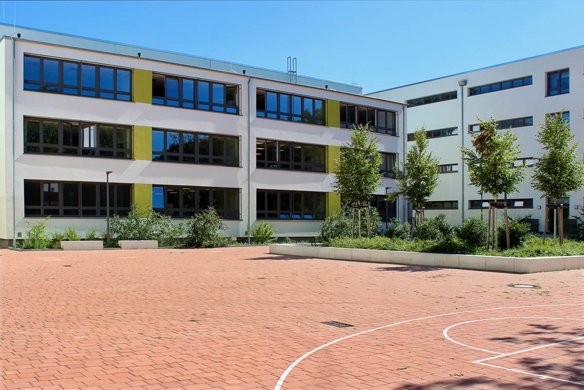 ein großes Gebäude mit einem Basketballplatz vorne - Referenzen von BAUSON GmbH aus Gräfenhainichen