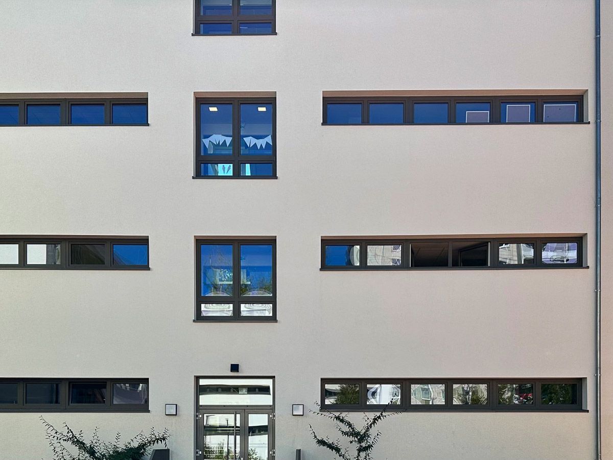 ein weißes Gebäude mit vielen Fenstern und einer Tür - Referenzen von BAUSON GmbH aus Gräfenhainichen