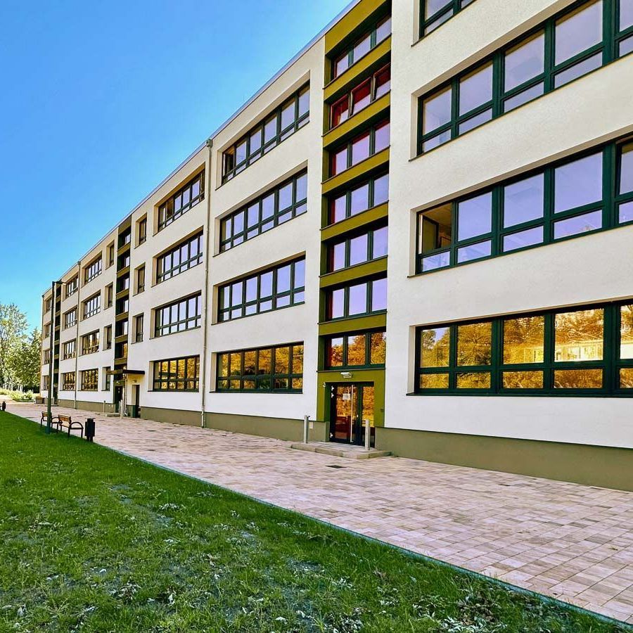 ein großes weißes Gebäude mit einem grünen Dach und vielen Fenstern - - Referenzen von BAUSON GmbH aus Gräfenhainichen