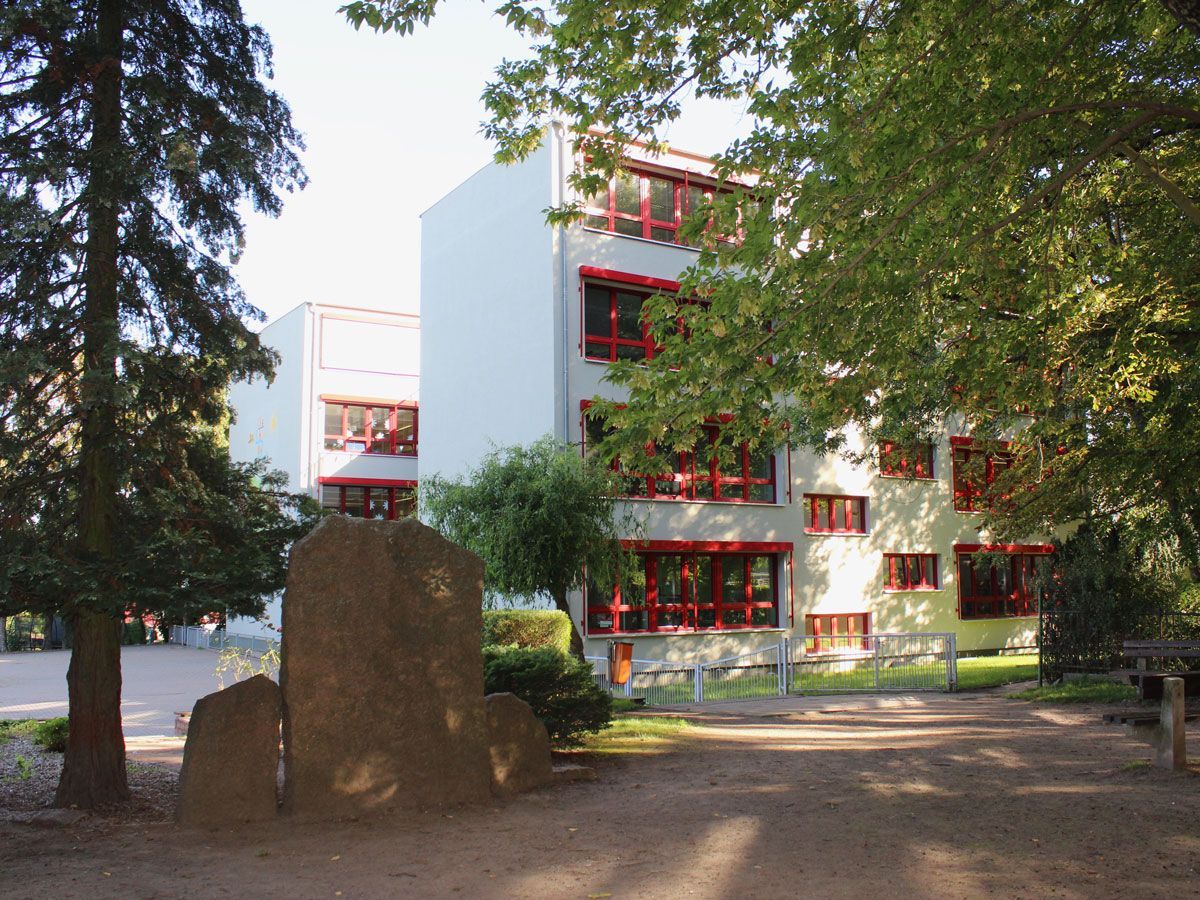 ein großes weißes Gebäude mit roten Fenstern und Bäumen davor - Referenzen von BAUSON GmbH aus Gräfenhainichen