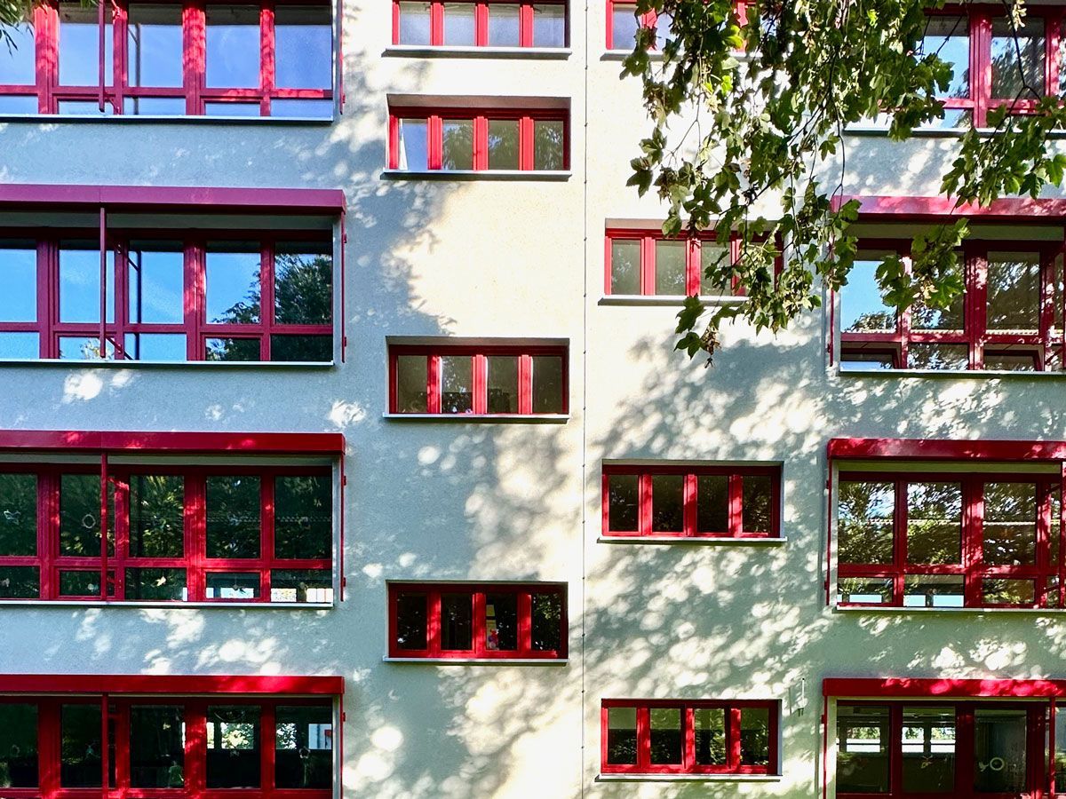 ein großes Gebäude mit vielen Fenstern und roten Fensterrahmen - Referenzen von BAUSON GmbH aus Gräfenhainichen