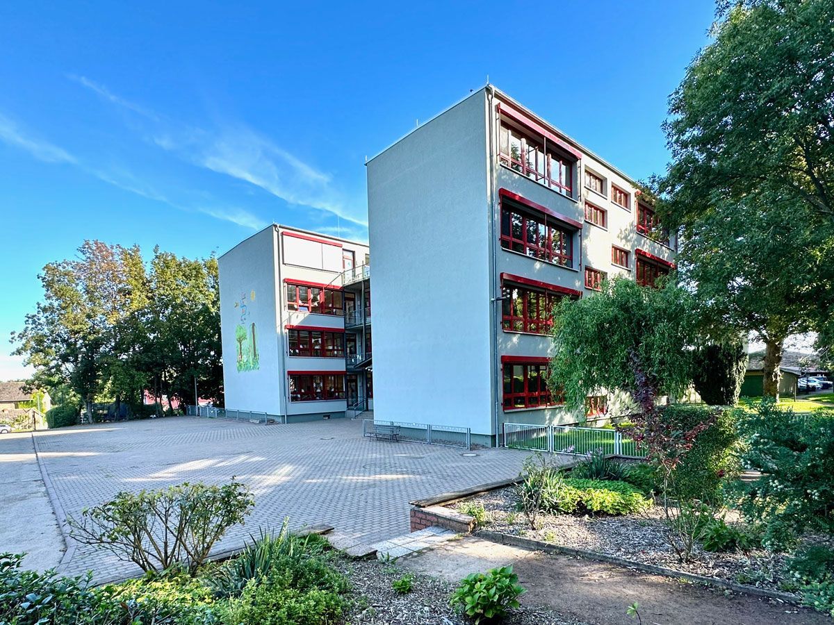 ein großes weißes Gebäude mit vielen Fenstern und Bäumen davor - Referenzen von BAUSON GmbH aus Gräfenhainichen