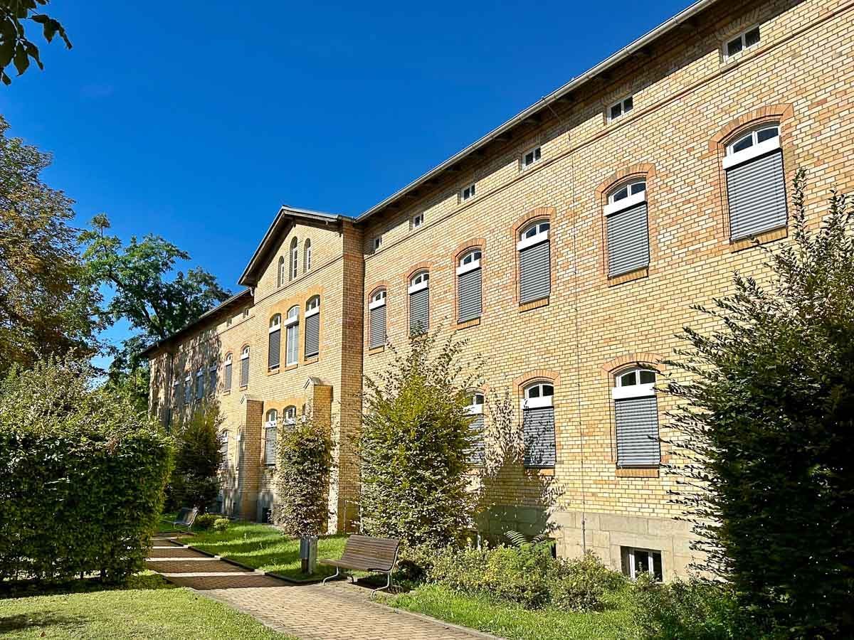 ein großes Backsteingebäude mit vielen Fenstern und Bäumen davor - Referenzen von BAUSON GmbH aus Gräfenhainichen