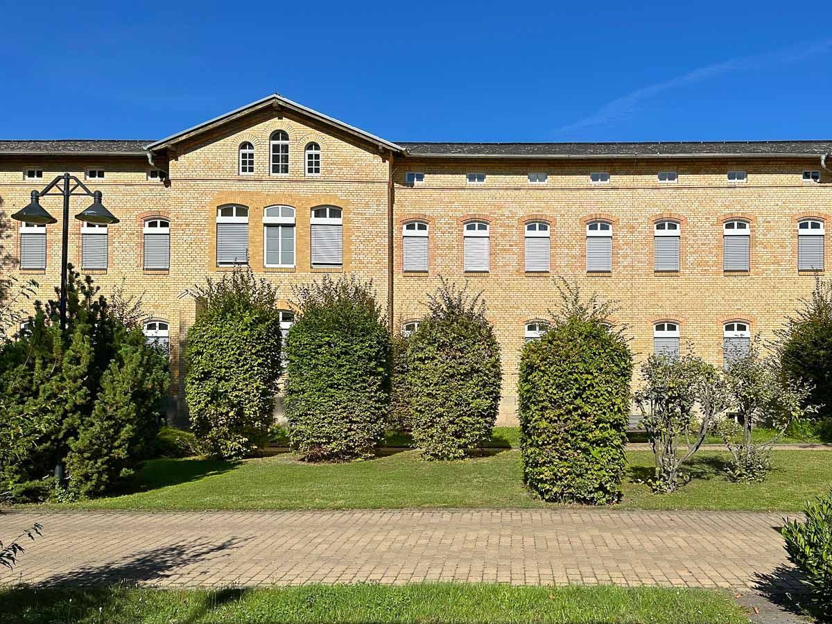 ein großes Backsteingebäude mit vielen Fenstern und Bäumen davor - Referenzen von BAUSON GmbH aus Gräfenhainichen