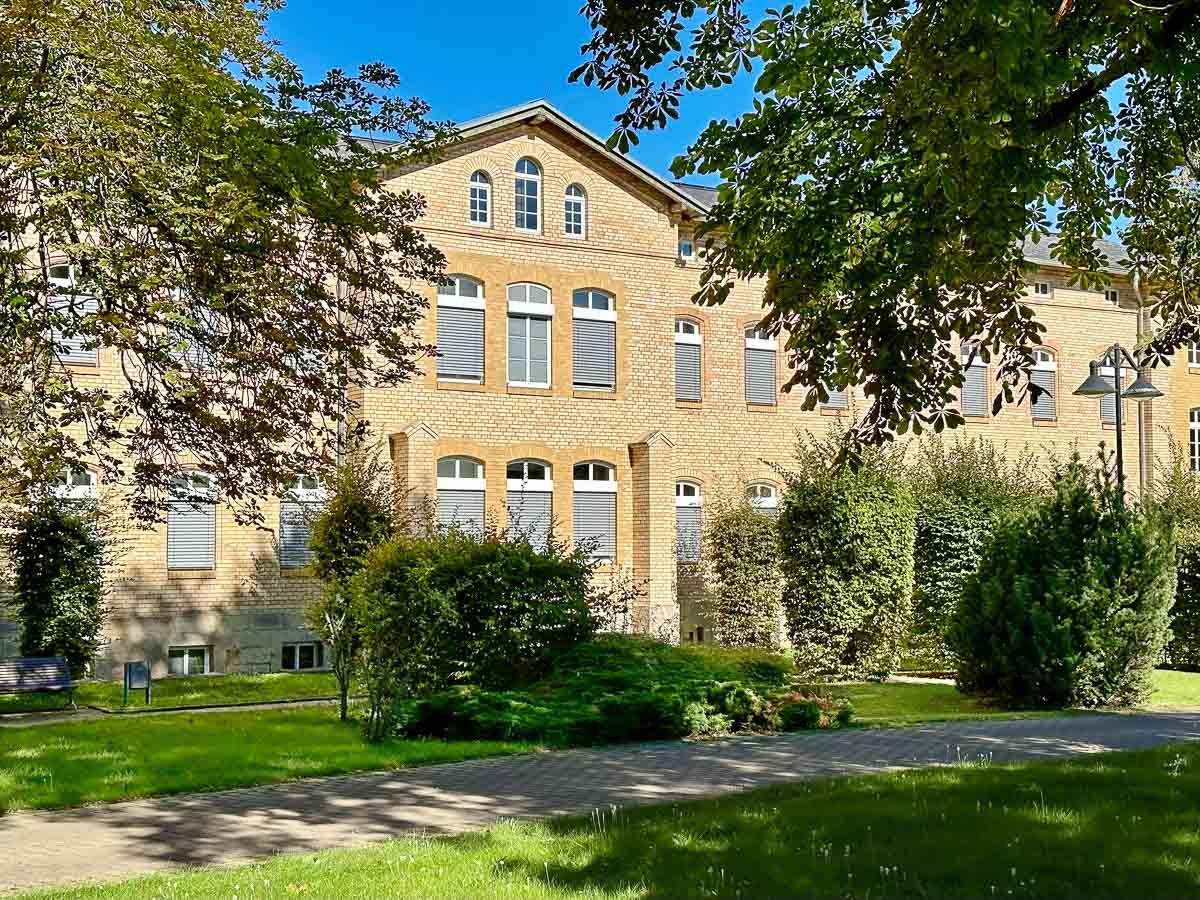 ein großes Gebäude mit vielen Fenstern und Bäumen davor - Referenzen von BAUSON GmbH aus Gräfenhainichen