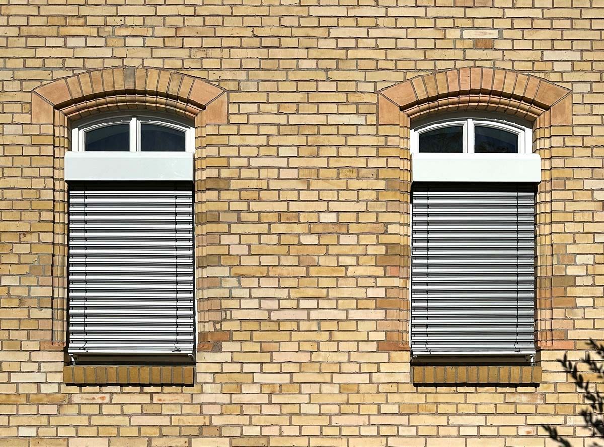 ein Backsteingebäude mit zwei Fenstern und Jalousien - Referenzen von BAUSON GmbH aus Gräfenhainichen