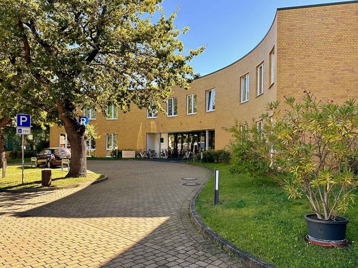 ein Gebäude mit einem gebogenen Eingang und einem Parkplatz davor - Referenzen von BAUSON GmbH aus Gräfenhainichen