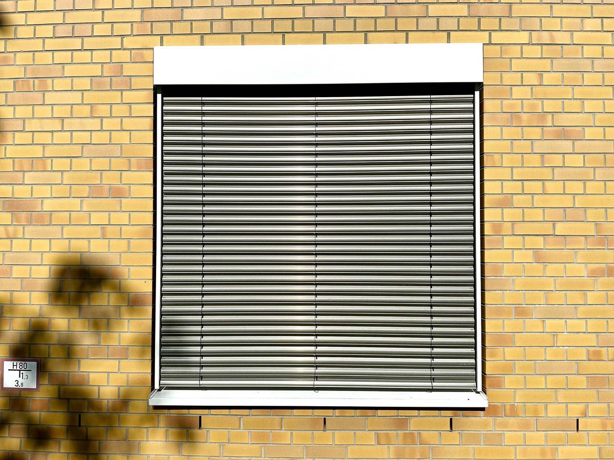 ein Fenster mit Jalousien an einer Backsteinmauer - Referenzen von BAUSON GmbH aus Gräfenhainichen