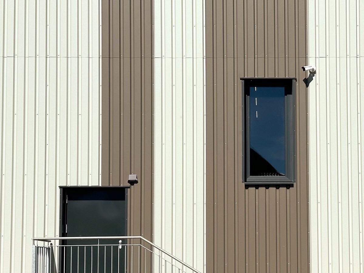 eine braun-weiße Gebäudefassade mit zwei Fenstern und einer Treppe - Referenzen von BAUSON GmbH aus Gräfenhainichen