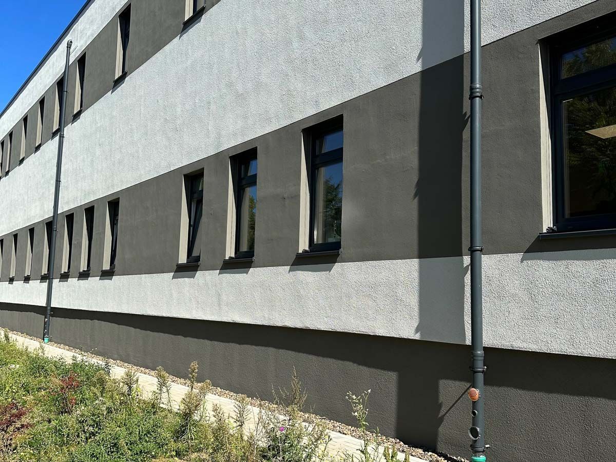 eine grau-weiße Gebäudefassade mit vielen Fenstern - Referenzen von BAUSON GmbH aus Gräfenhainichen