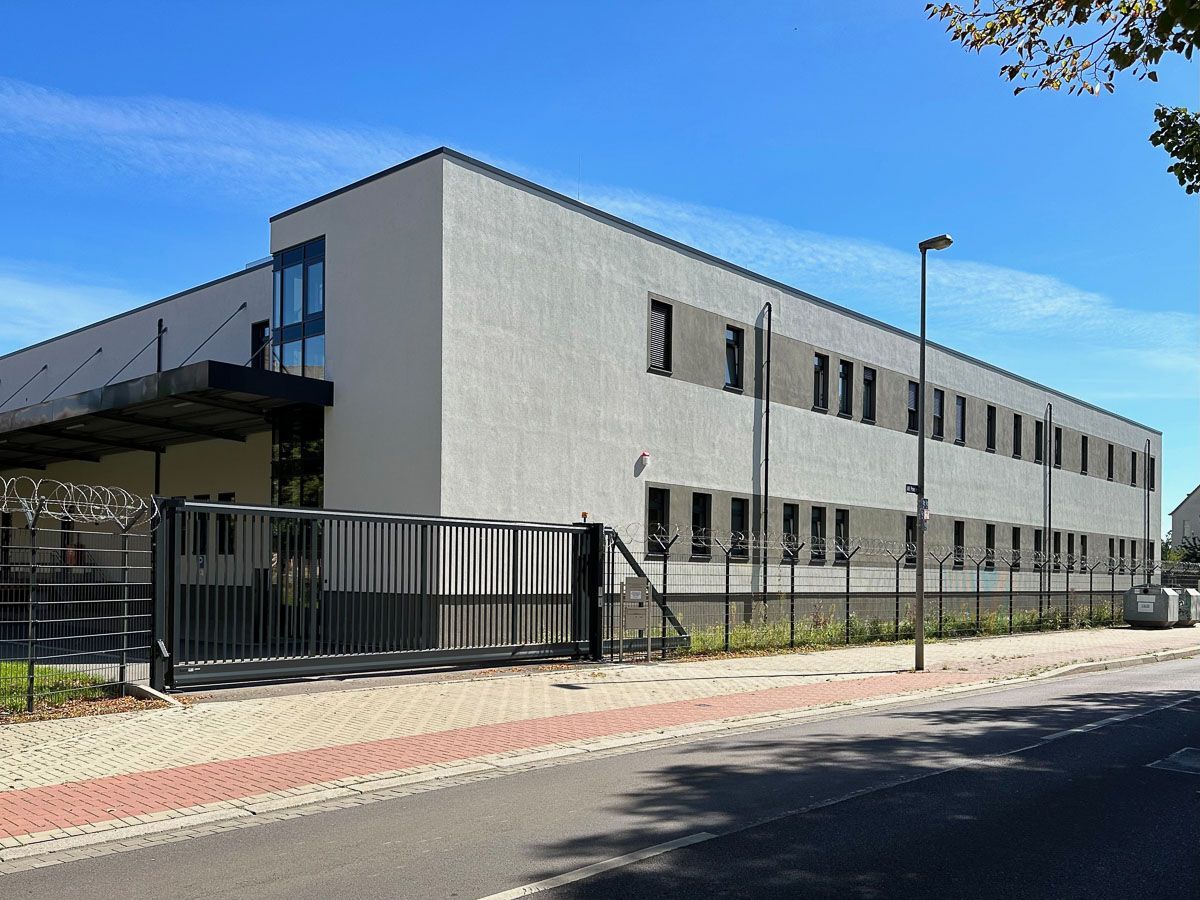 ein großes weißes Gebäude mit einem Zaun davor - Referenzen von BAUSON GmbH aus Gräfenhainichen