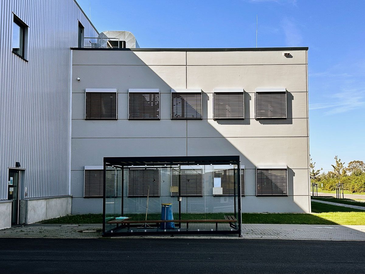 eine Bushaltestelle vor einem großen Gebäude mit vielen Fenstern - Referenzen von BAUSON GmbH aus Gräfenhainichen