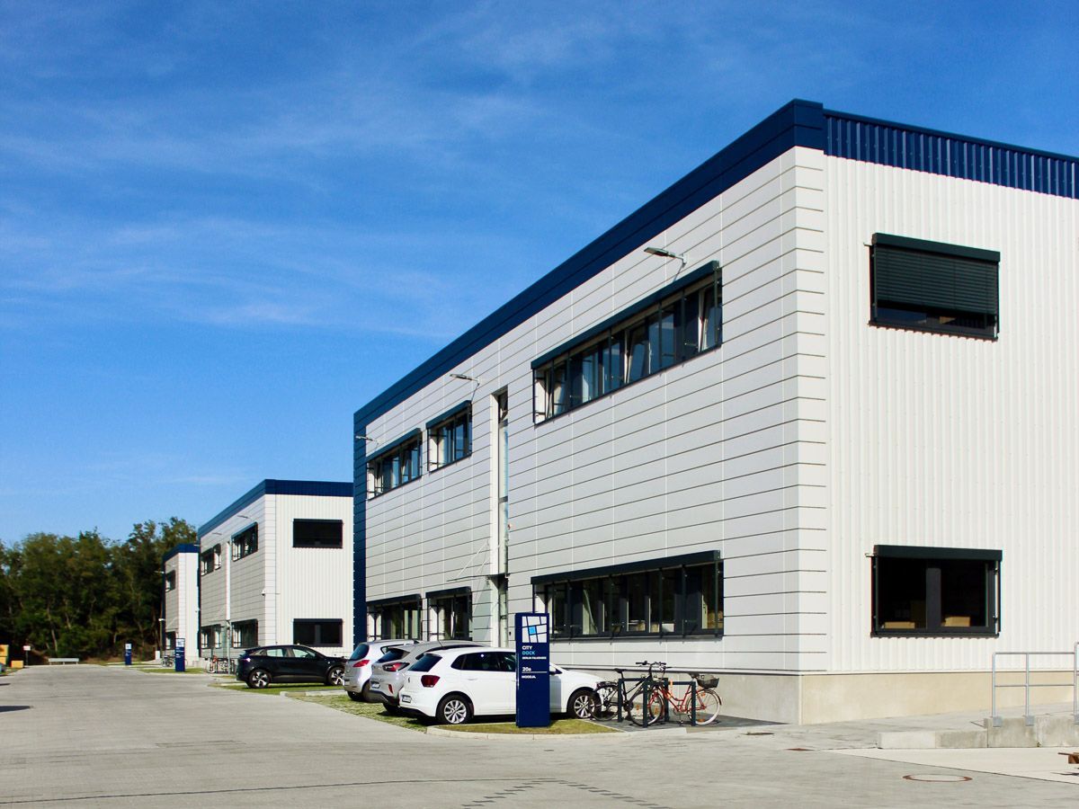 ein großes weißes und blaues Gebäude mit vielen Autos davor geparkt - Referenzen von BAUSON GmbH aus Gräfenhainichen