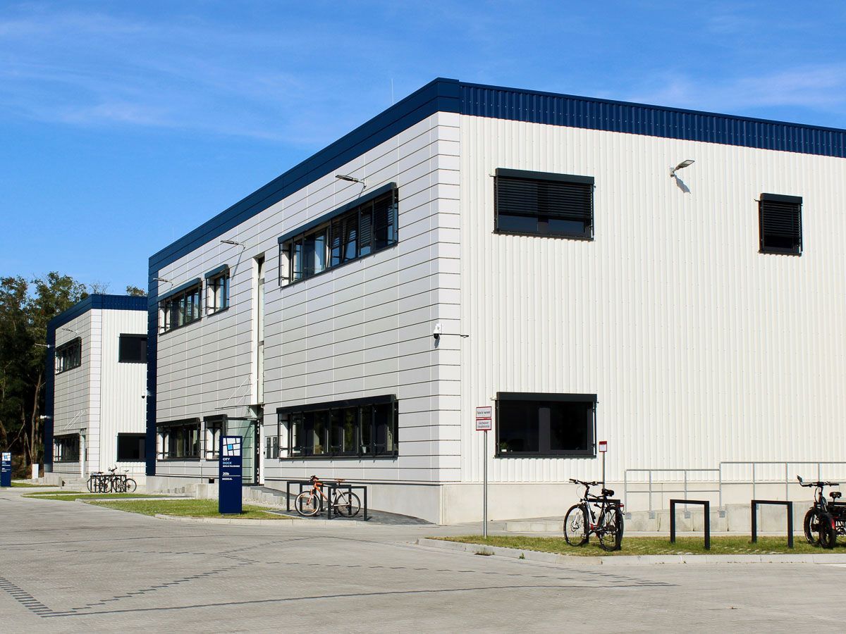 ein großes weißes Gebäude mit einem blauen Dach - Referenzen von BAUSON GmbH aus Gräfenhainichen