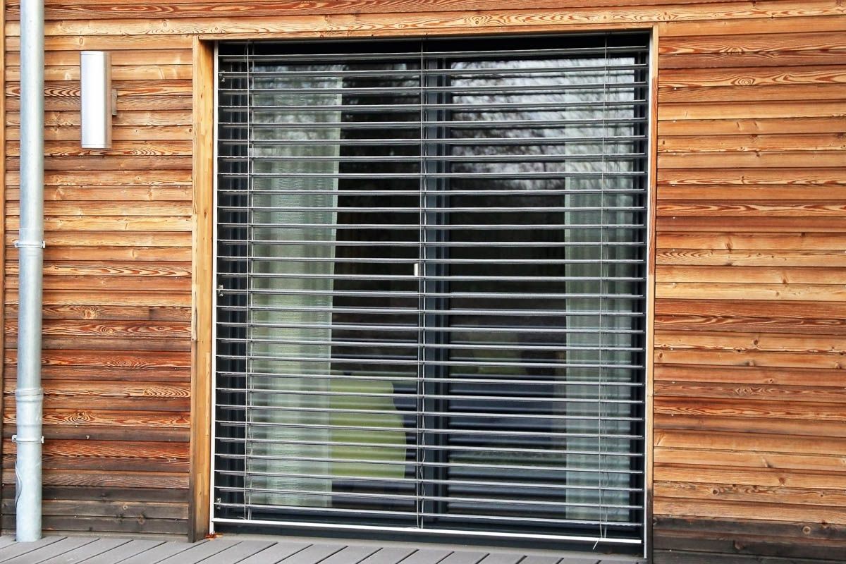 ein Haus mit einer Holzfassade und einer Schiebetür mit Jalousien  - Sonnenschutz von Warema - eingebaut von BAUSON GmbH aus Gräfenhainichen