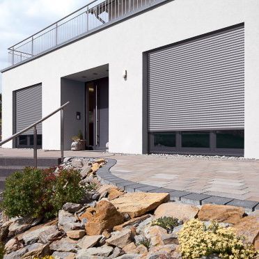 ein weißes Haus mit Rollläden und einem Balkon - Sonnenschutz von Warema - eingebaut von BAUSON GmbH aus Gräfenhainichen