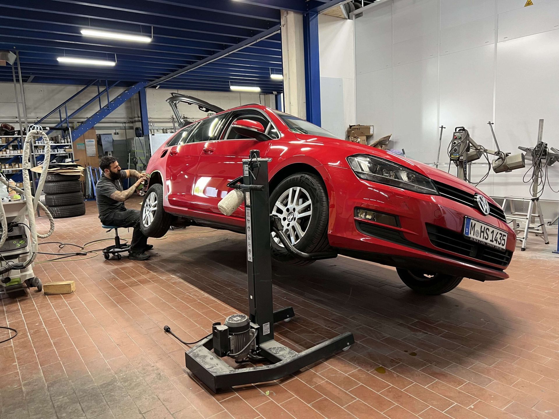 Rotes Auto seitlich angehoben in einer KFZ Werkstatt