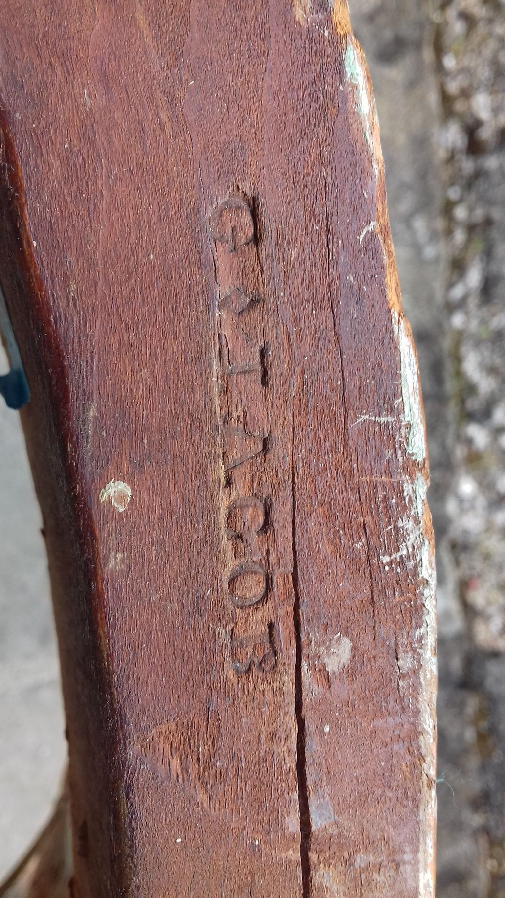 Pourtour de fauteuil abîmé avec inscription gravée dans le bois