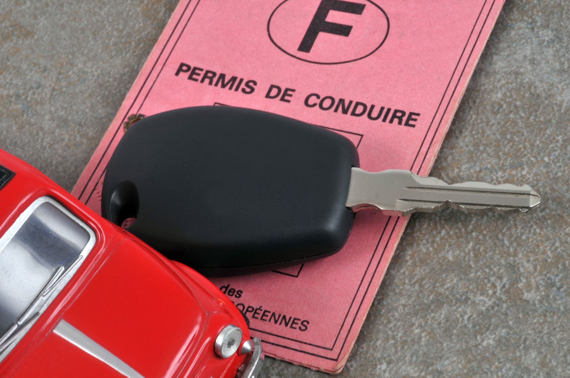 Clé de voiture sur un permis de conduire français, avec une petite voiture.