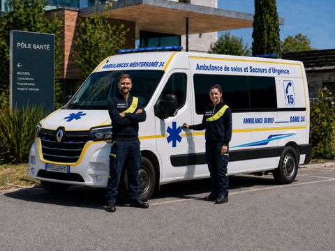 Camionnette médicale blanche et jaune garée devant un bâtiment.