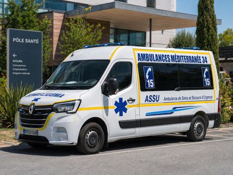 Camionnette médicale blanche et jaune garée devant un bâtiment.