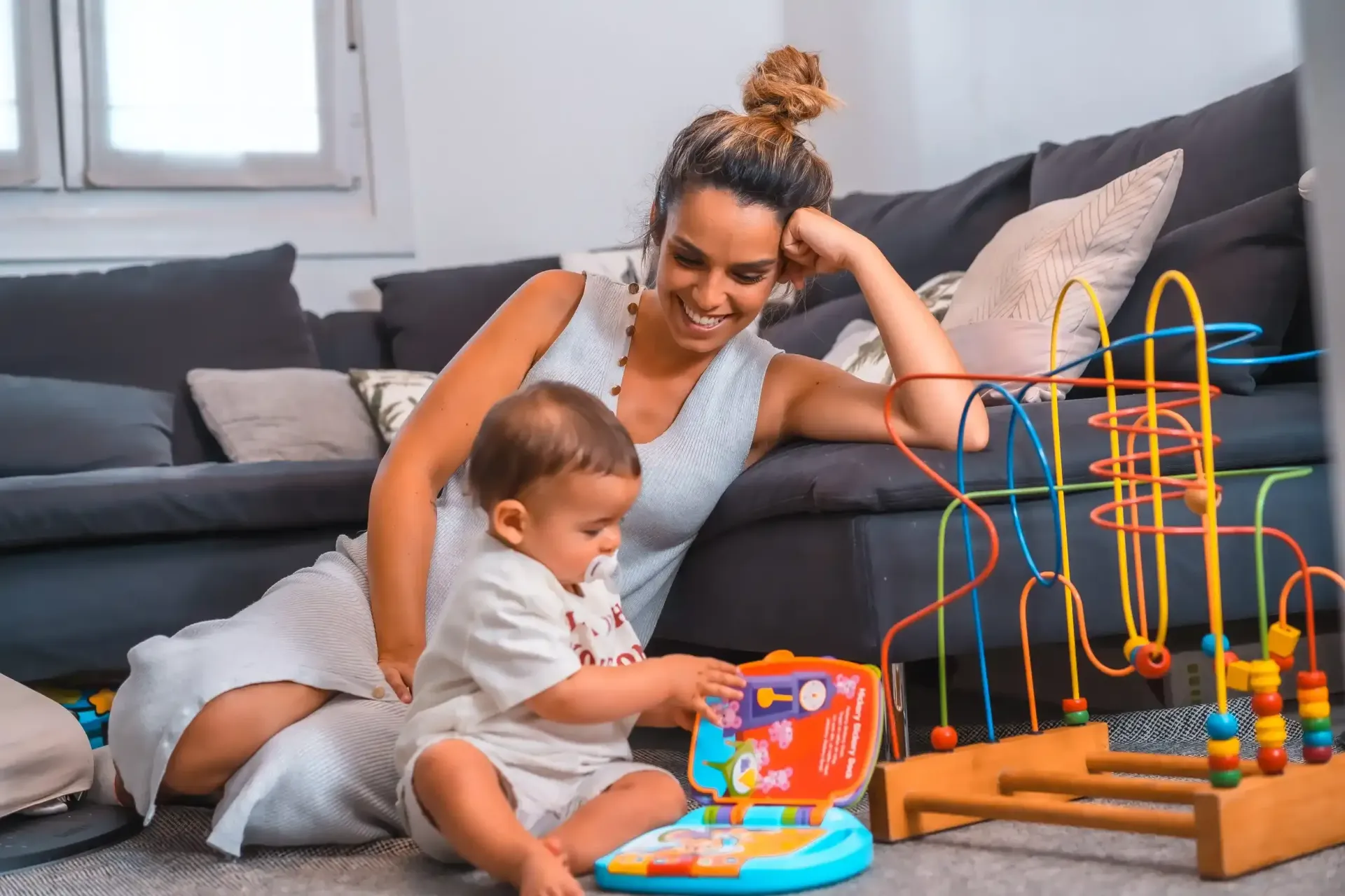 Una persona está sentada en el suelo observando a un niño pequeño