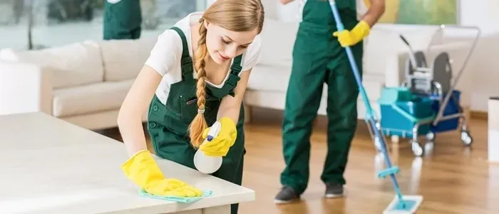 Personal de limpieza con uniformes verdes trabajando en una casa