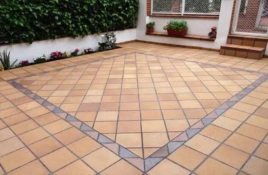Un patio con baldosas cuadradas de color marrón claro
