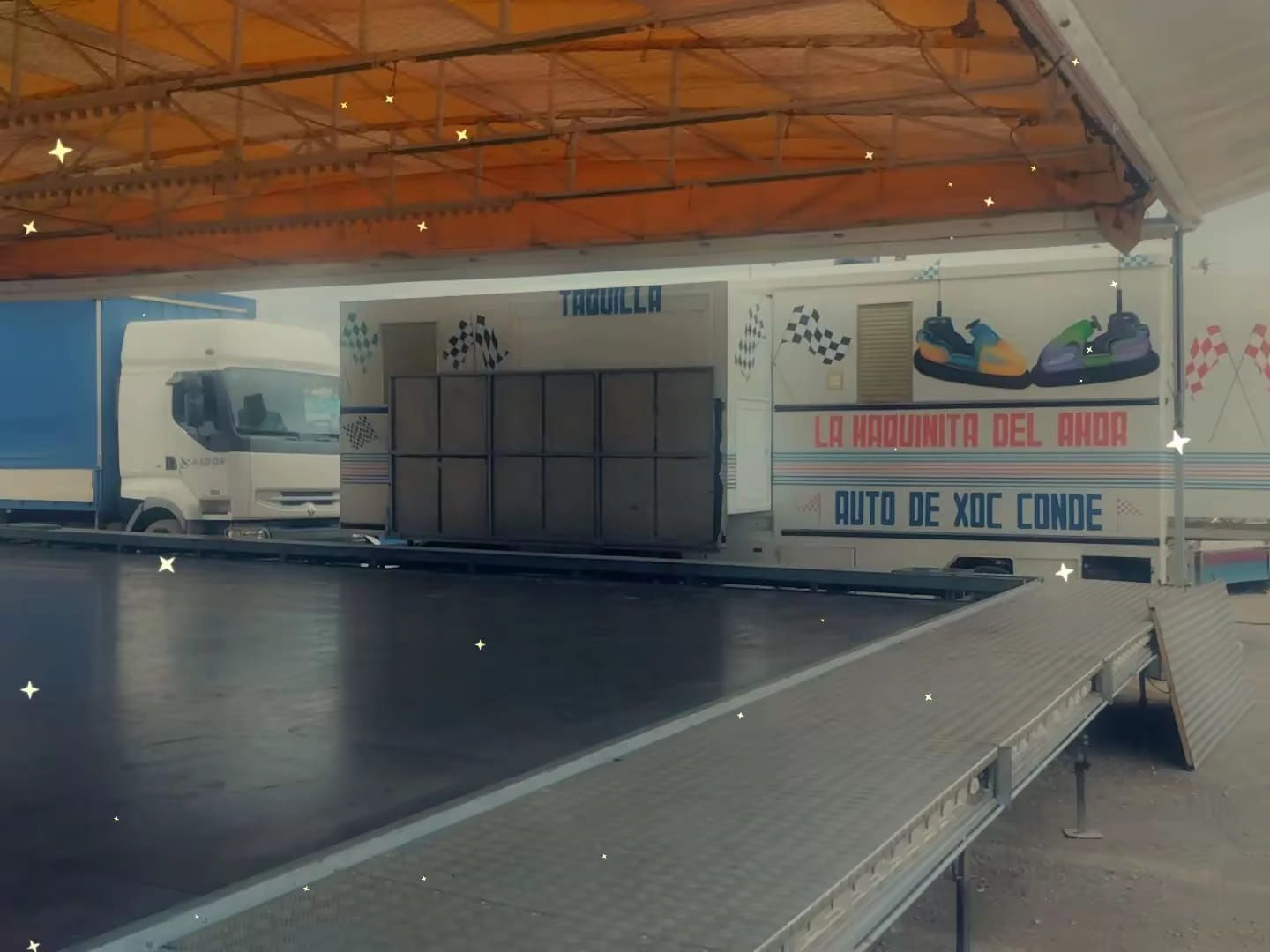 Montaje de un paseo en autos chocadores, que incluye un camión, cajas y un mural de un zapato y texto en español.