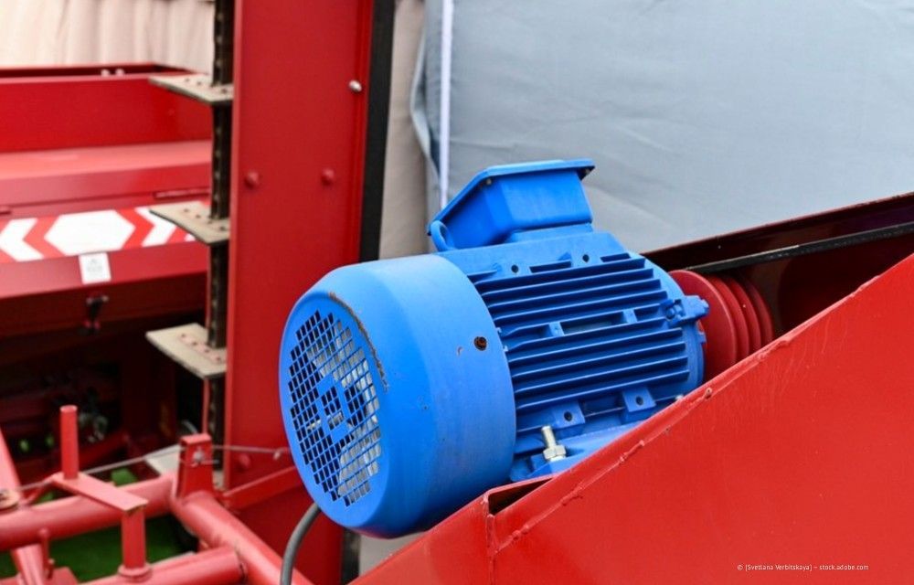 Blauer Elektromotor, montiert auf rotem Maschinenrahmen in einer industriellen Umgebung