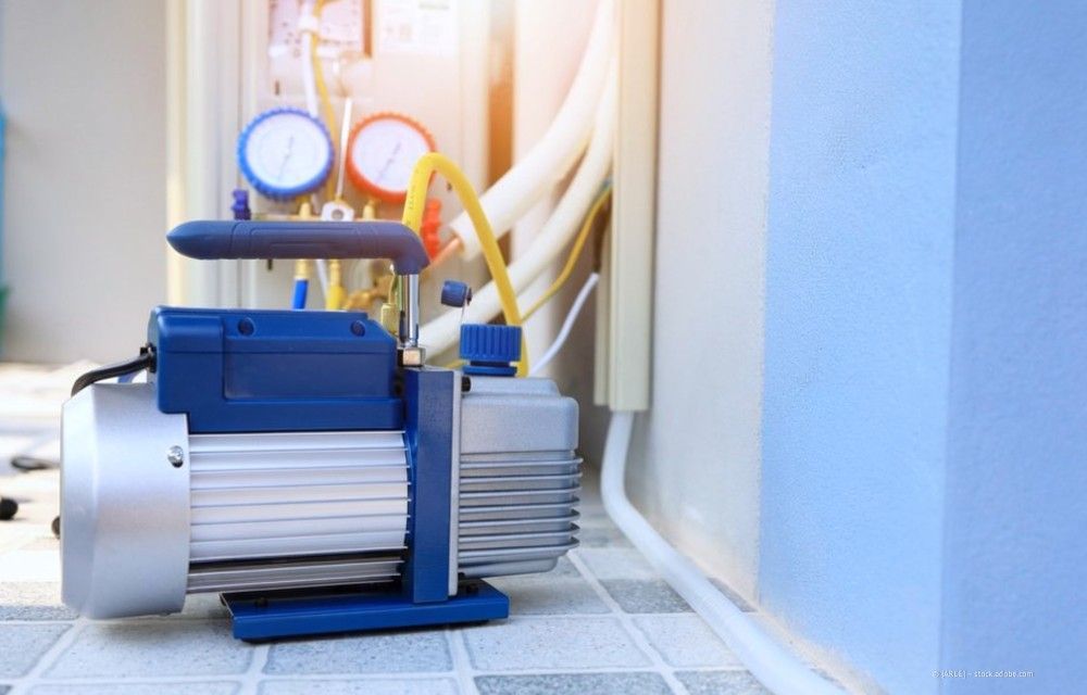 Blaue und silberne Industriepumpe mit Manometern und Schläuchen in einem Hauswirtschaftsraum