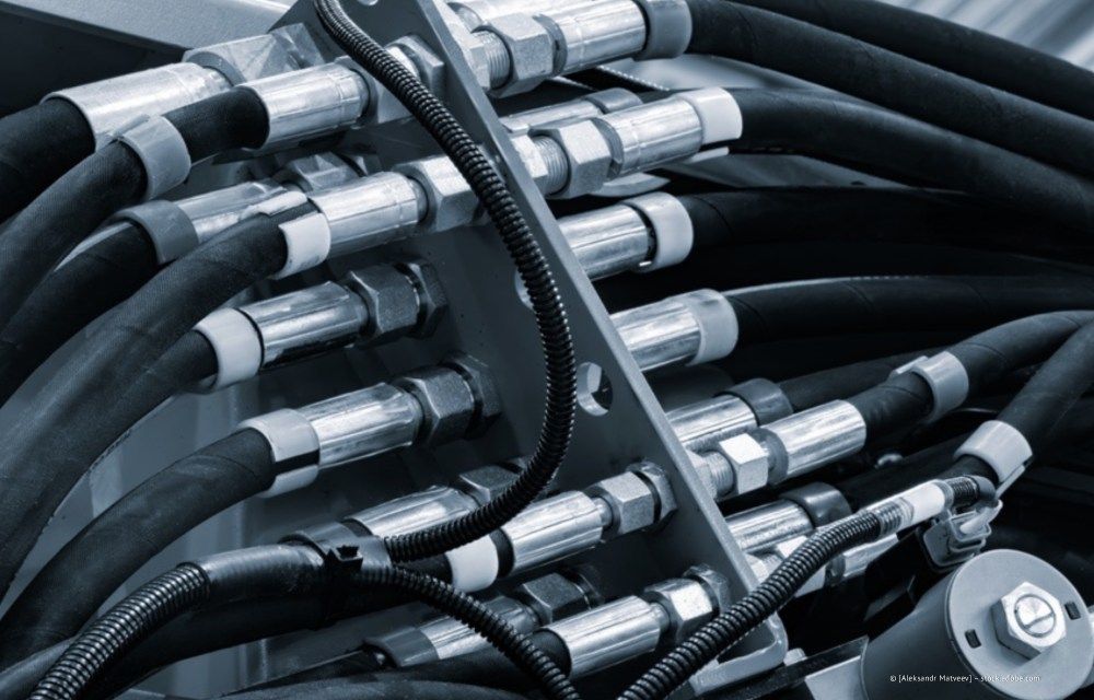 Nahaufnahme von gebündelten schwarzen Hydraulikschläuchen mit silbernen Metallarmaturen und -verbindern