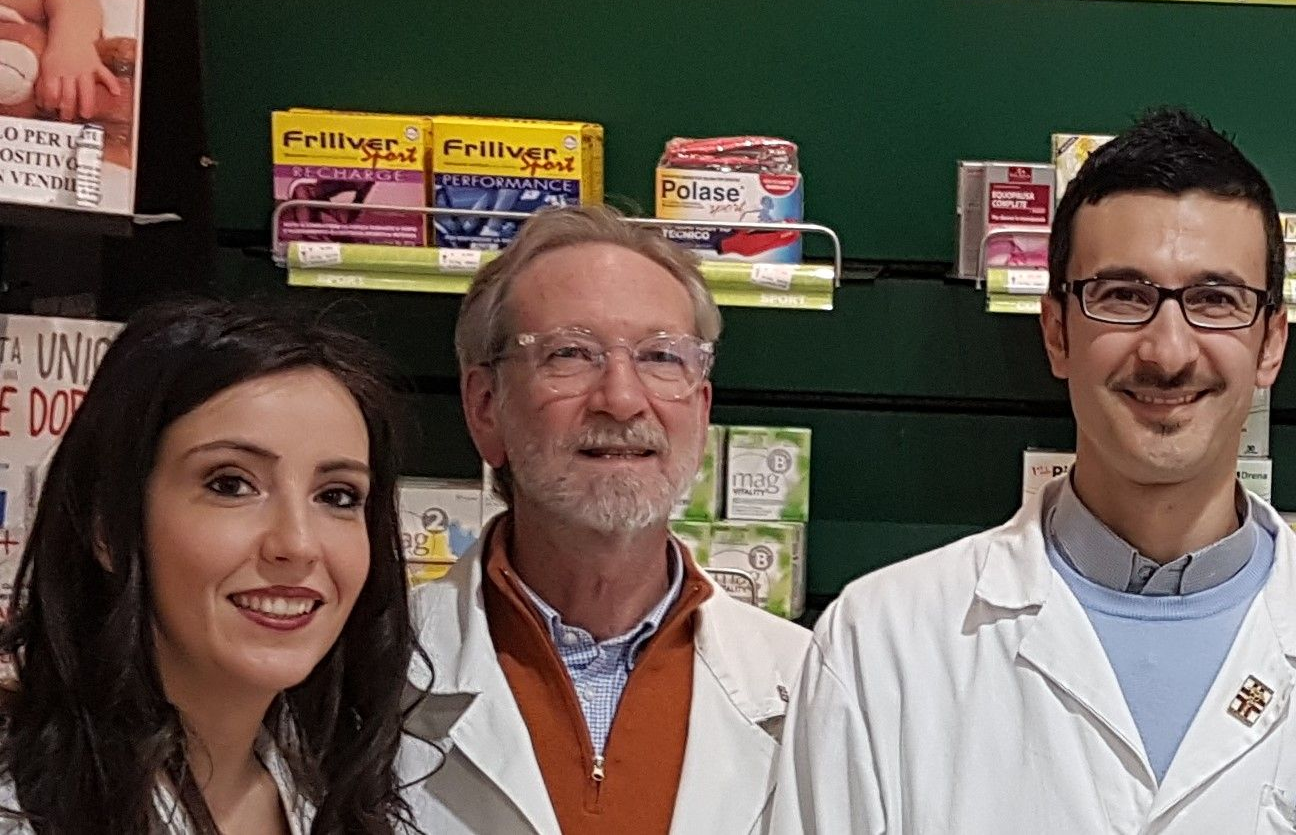 Dentista in camice bianco che mostra le radiografie dentali a un paziente. Sorride indossando guanti blu.