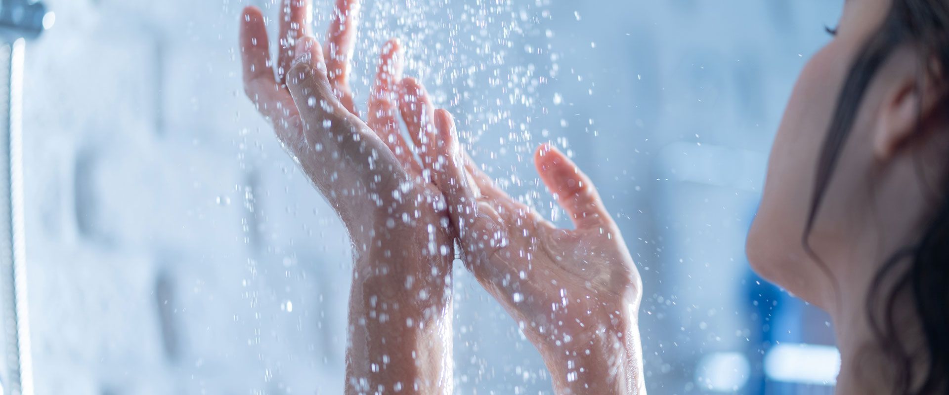 Une femme passant ses mains sous l'eau de la douche