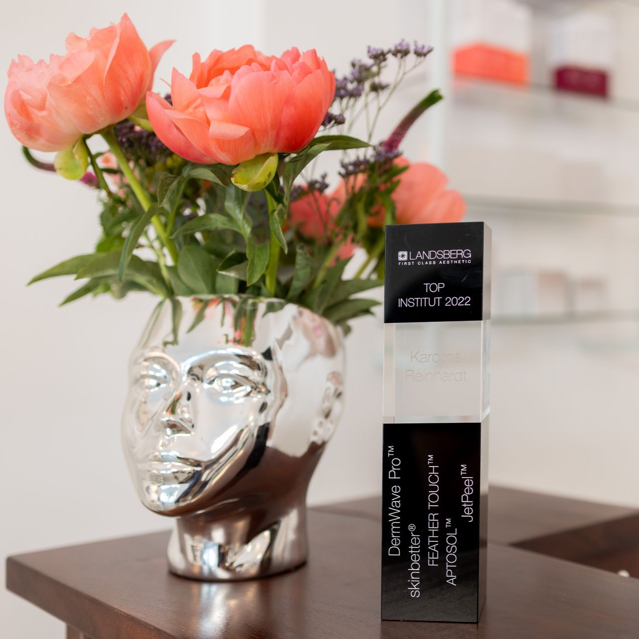 Auf einem Tisch steht neben einer Kiste eine Vase mit Blumen.