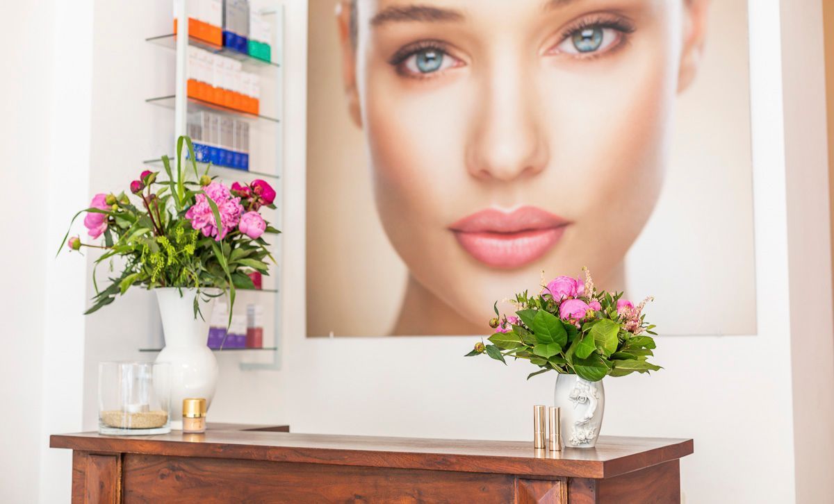 An der Wand über einem Holztisch hängt das Bild eines Frauengesichts.