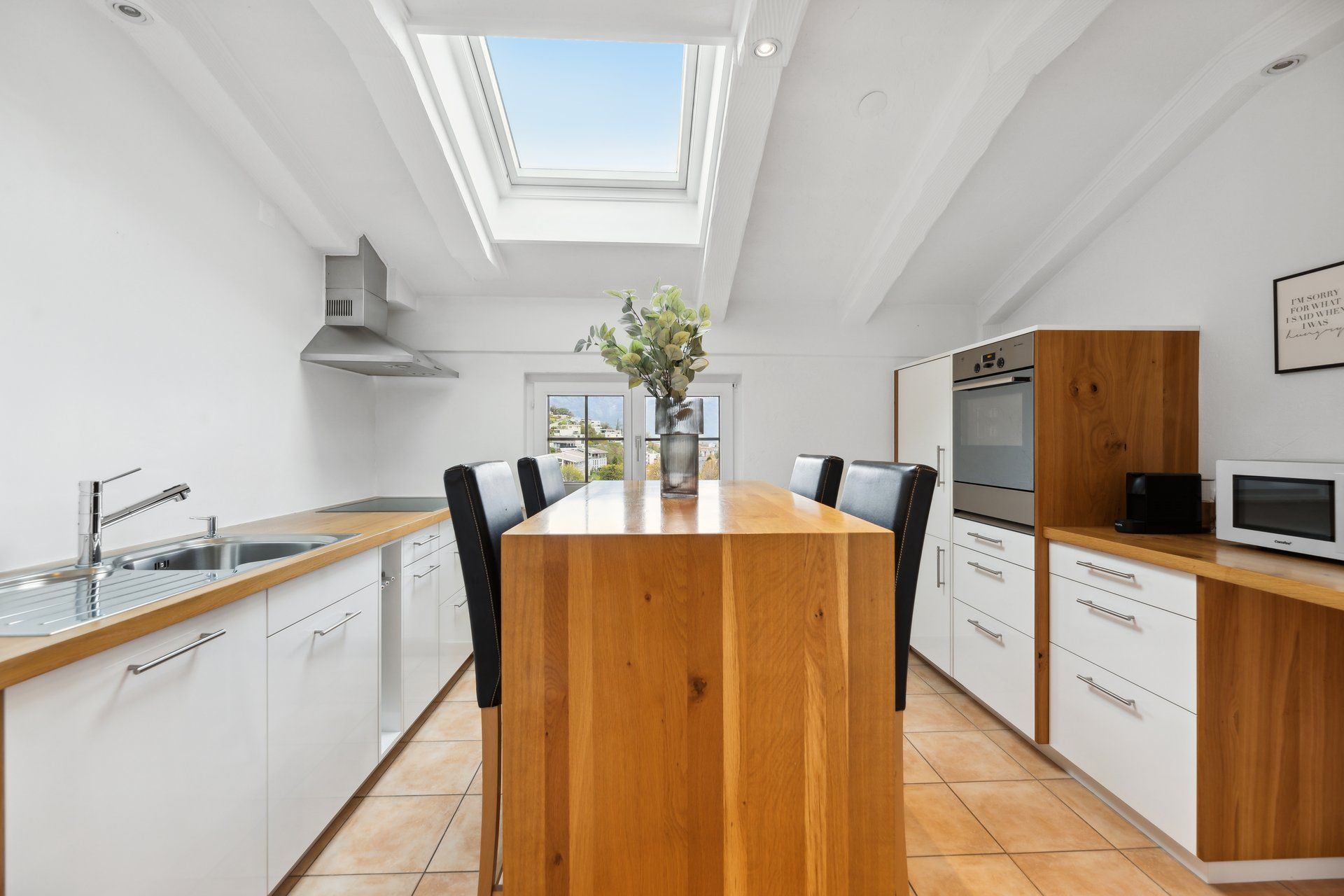 A kitchen with a wooden table and chairs and a skylight.