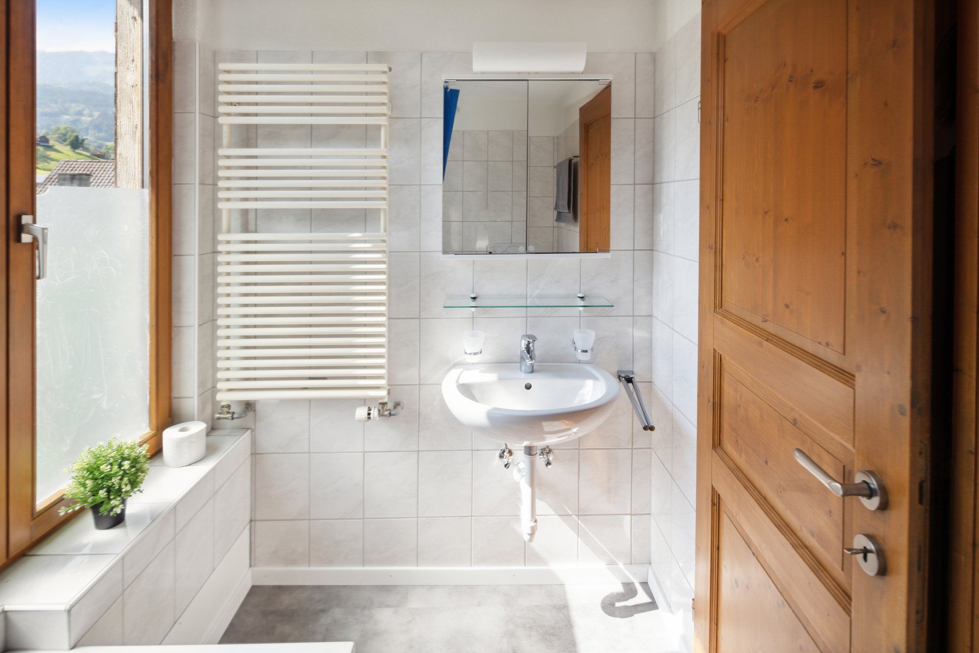 A bathroom with a sink , towel rack , mirror and window.