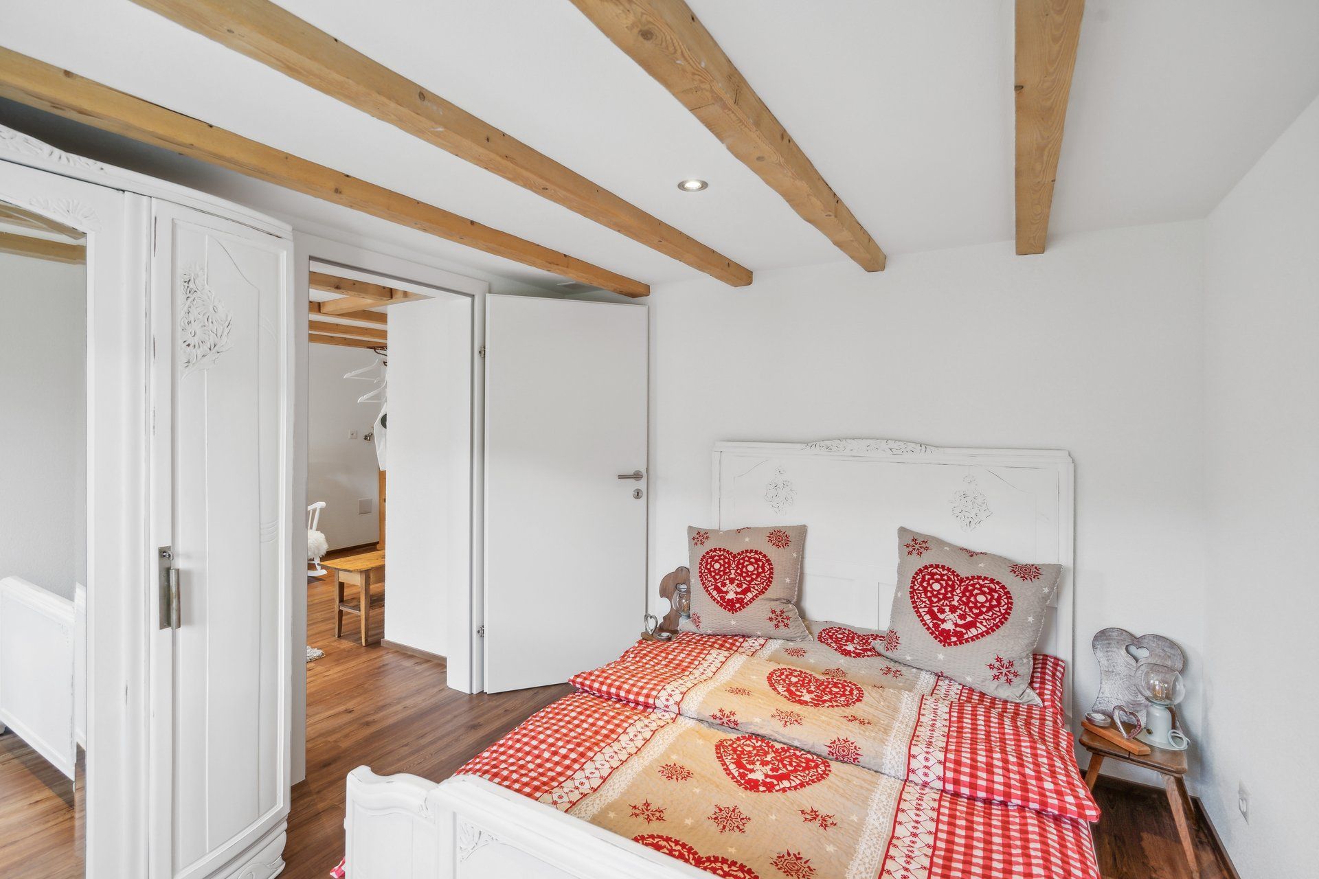 A bedroom with a bed and a wardrobe with wooden beams.