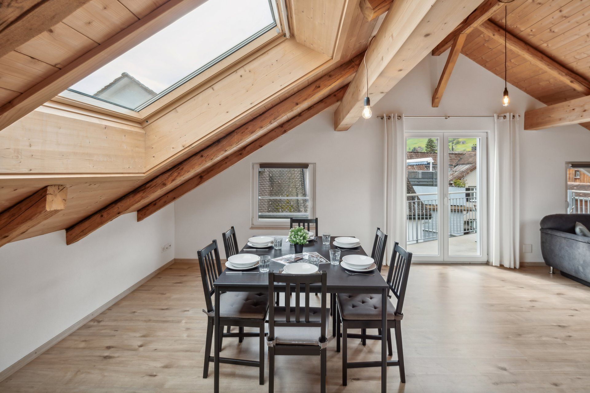 A dining room with a table and chairs under a skylight.