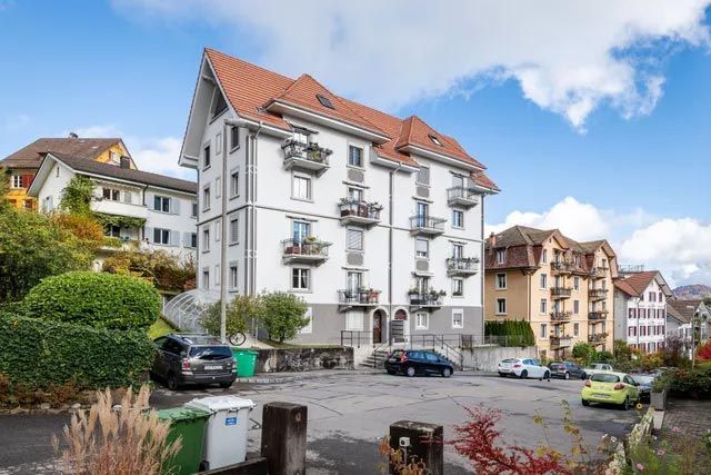 Die Liegenschaftsverwalter AG - Weisses Mehrfamilienhaus mit Parkplatz