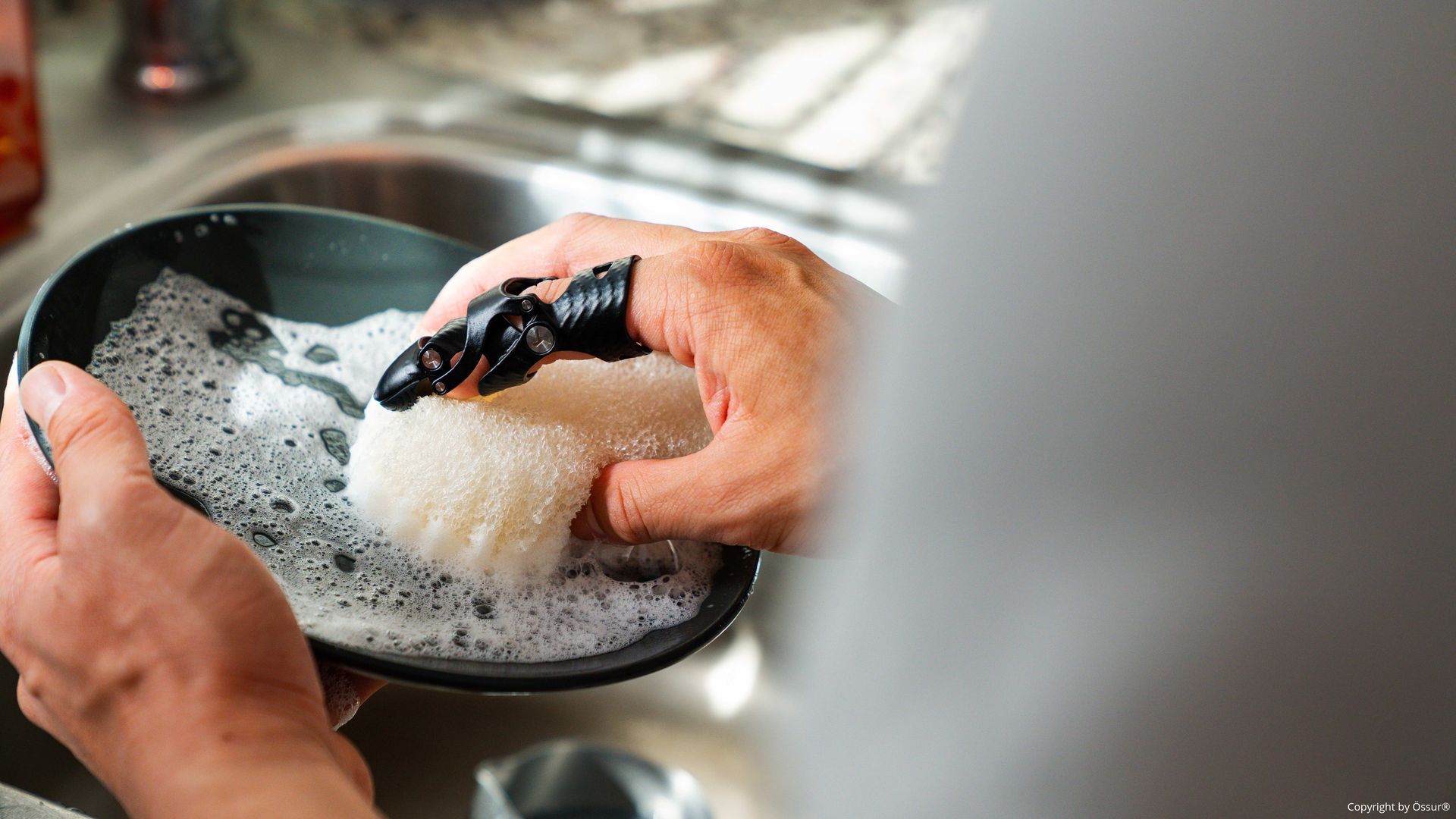 Ein Mann spült einen Teller mit einer Fingerprothese