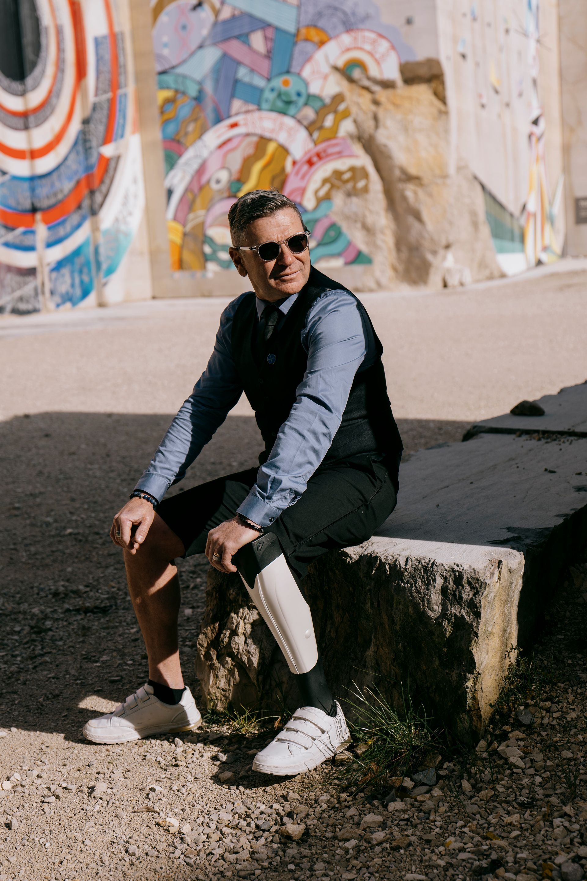 Schick gekleideter Mann mit Beinprothese sitzt auf einem Stein